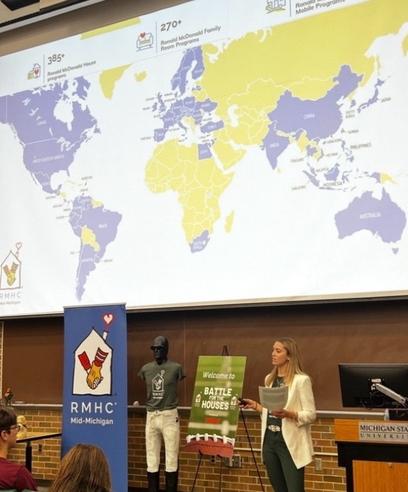 a woman presents with a map of the world behind her