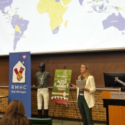 a woman presents with a map of the world behind her