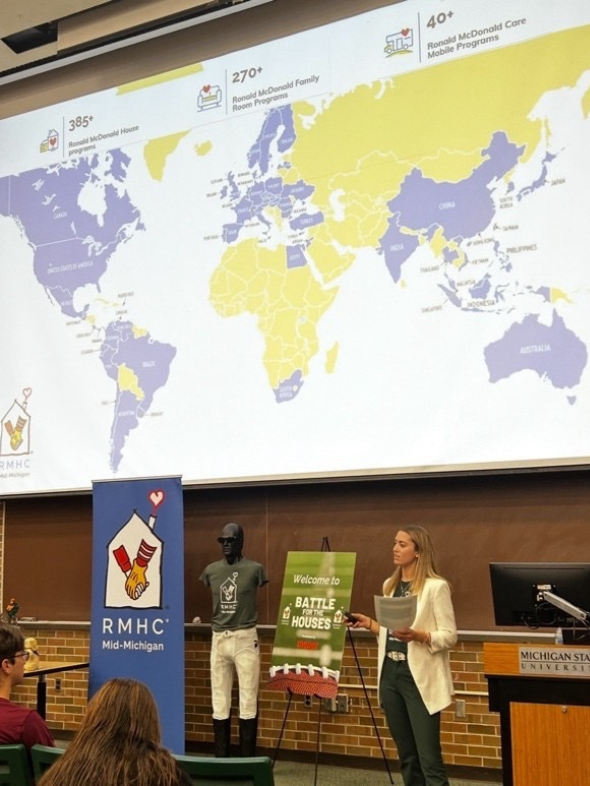 a woman presents with a map of the world behind her