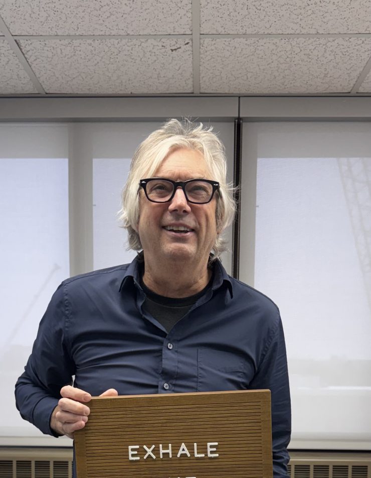 a man smiles holding an exhale card