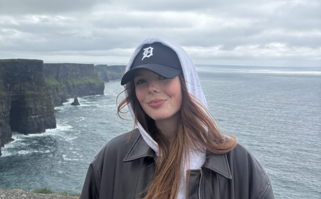 a person smiling on the edge of cliffs near the Atlantic ocean