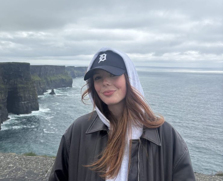 a person smiling on the edge of cliffs near the Atlantic ocean