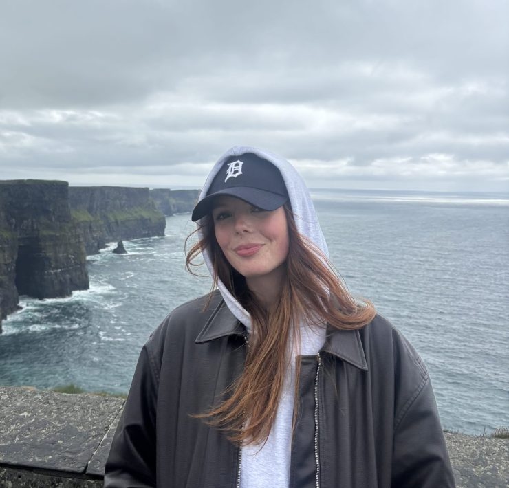 a person smiling on the edge of cliffs near the Atlantic ocean