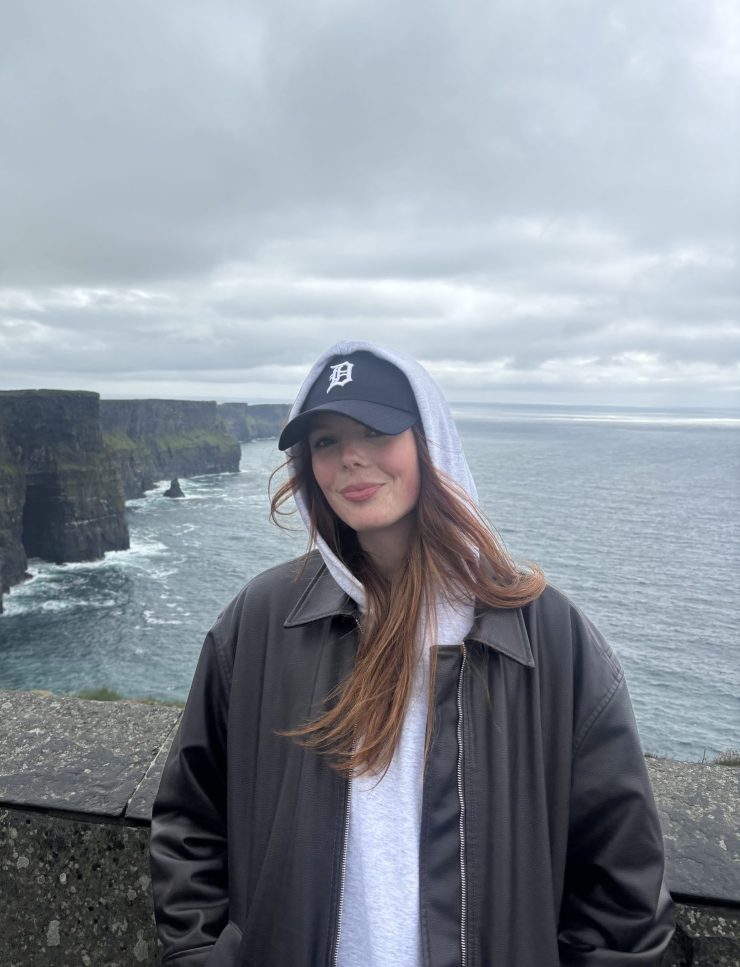 a person smiling on the edge of cliffs near the Atlantic ocean