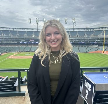 A woman smiles with a baseball stadium in the background