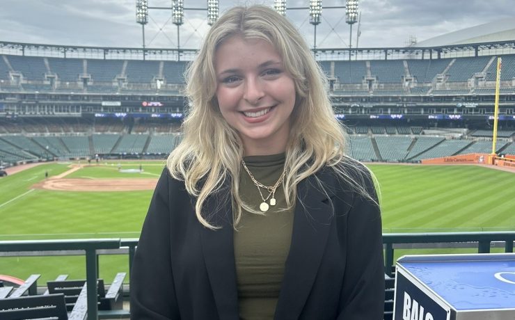 A woman smiles with a baseball stadium in the background
