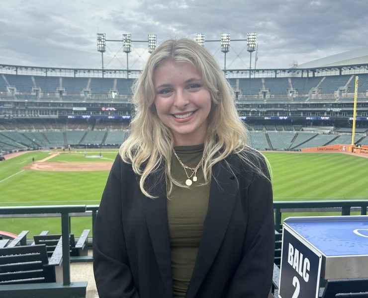 A woman smiles with a baseball stadium in the background