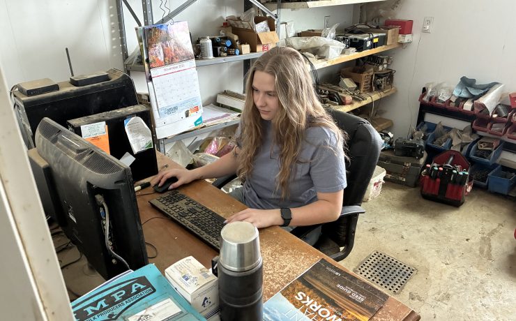 A person happily works on a computer at a desk in a room